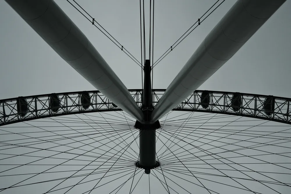 An upward view of the supports, cables and rim of a Ferris wheel