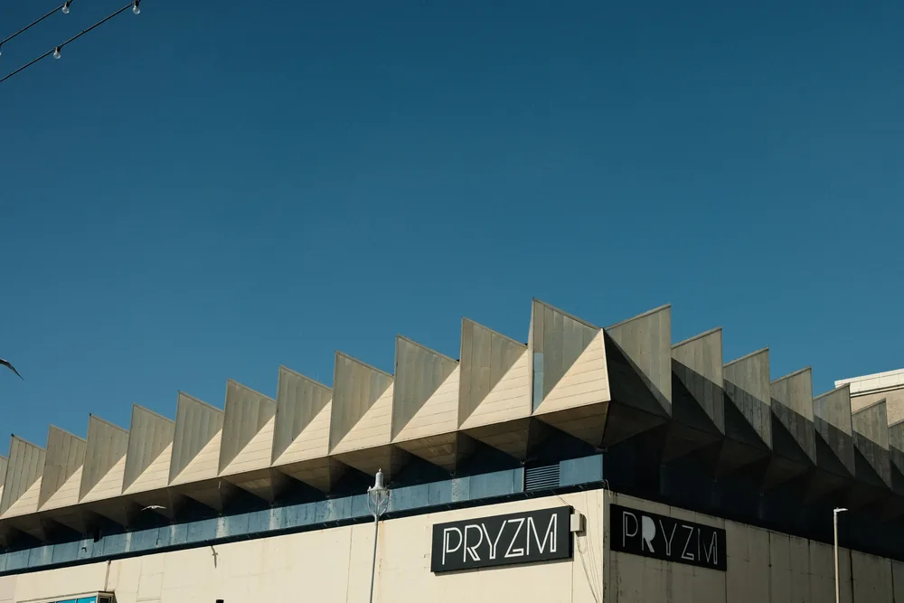 The concrete facade of the PRYZM building with rows of projecting triangular forms