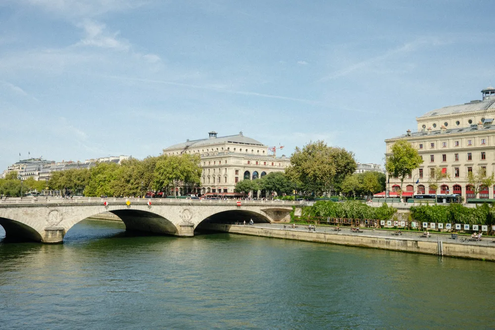 A stone arch bridge over the Seine, with trees and pale buildings along the embankment